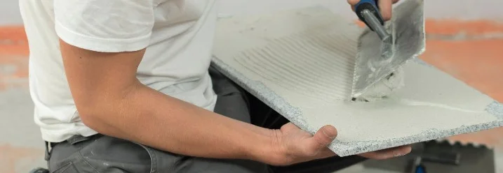 Person trägt Fliese mit Kleber